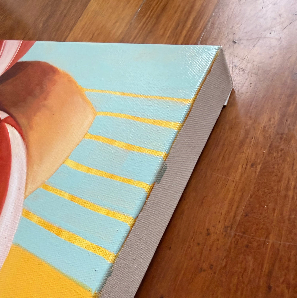 A close-up of a canvas painting on a wooden floor, showing a light blue background with yellow stripes, a yellow block, and part of a brown and red abstract shape.