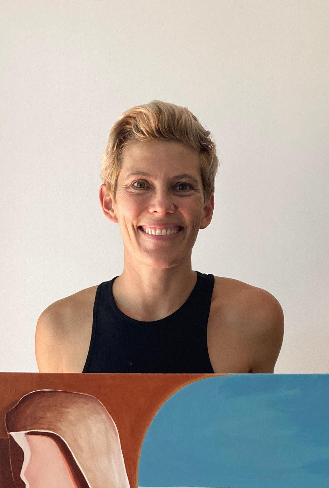 Photo of Australian Artist Michelle Macnamara with a canvas painting in her Byron bay art studio