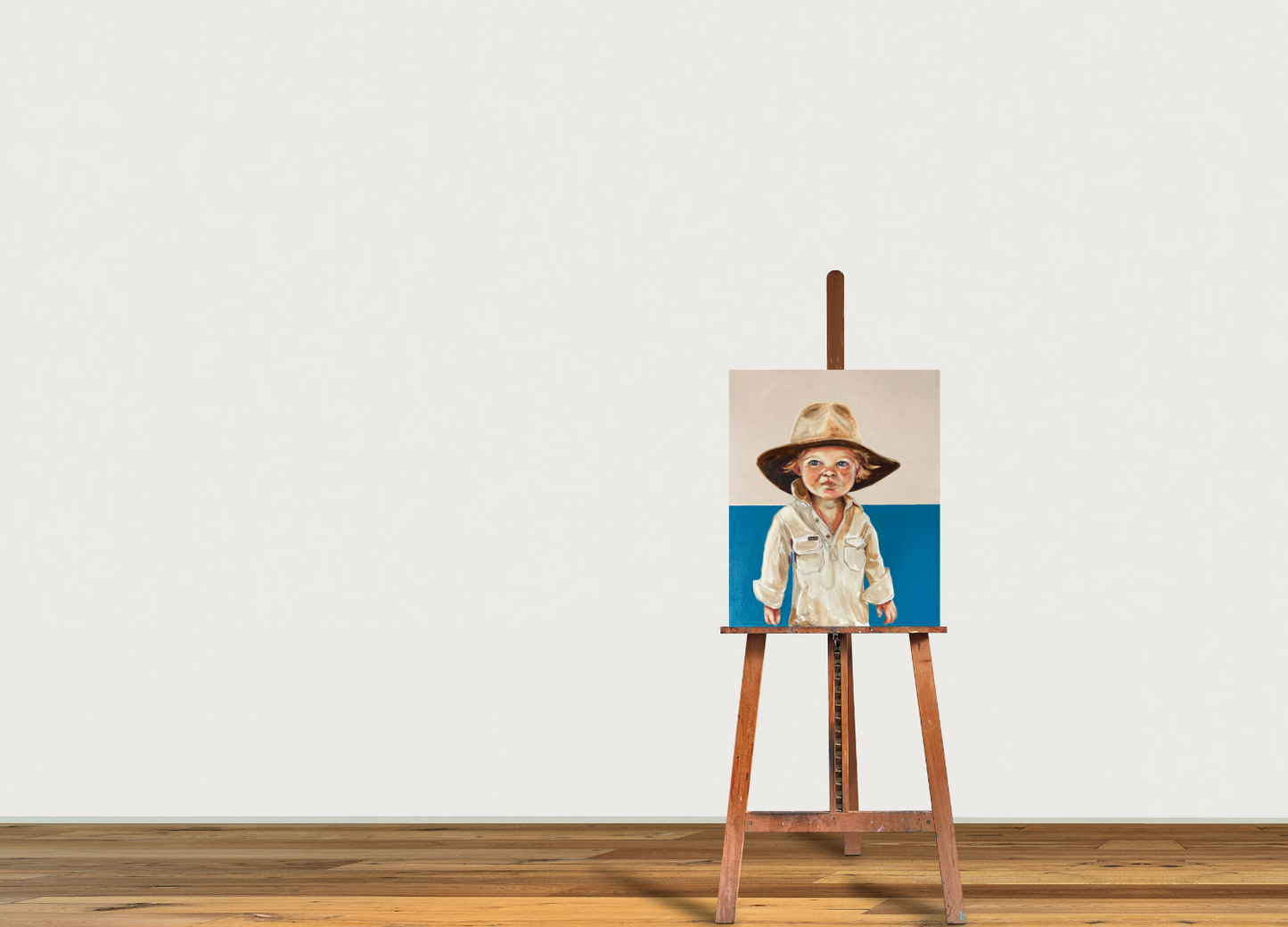 A hand-painted portrait of a child wearing a hat, set against a blue background, displayed on a wooden easel.